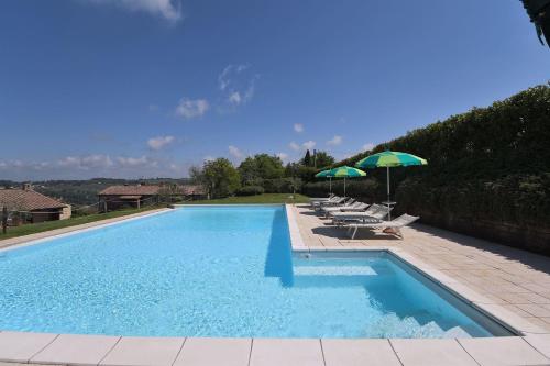 a swimming pool with lounge chairs and umbrellas at Casale Vecchio Fienile in SantʼAppiano