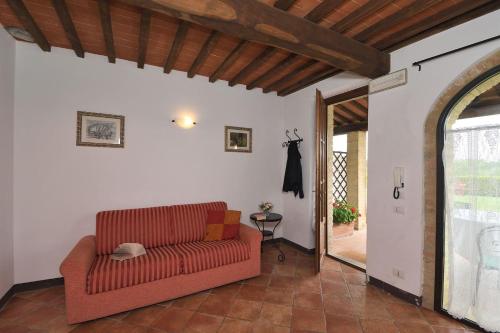a living room with a red couch and an open door at Casale Vecchio Fienile in SantʼAppiano