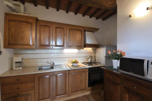 a kitchen with wooden cabinets and a sink and a microwave at Casale Vecchio Fienile in SantʼAppiano