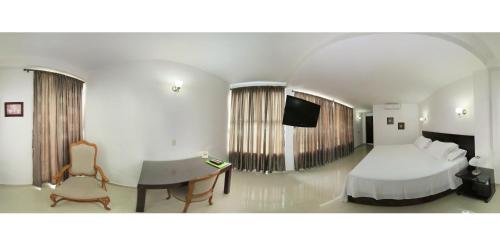 a hotel room with a bed and a table and a desk at Hotel Estrella Palmira in Palmira