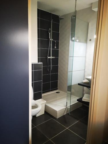 a bathroom with a toilet and a glass shower at Hôtel Bar Brasserie L'ESCALE in Bergerac