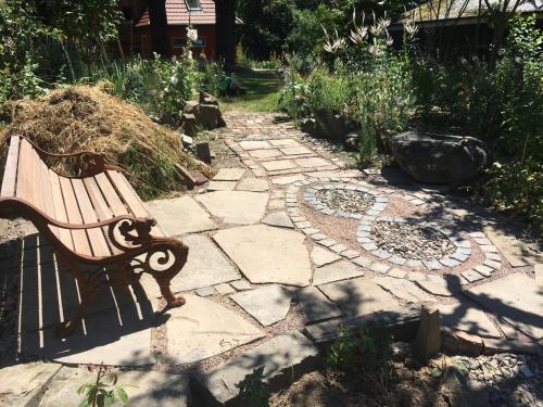 a wooden bench sitting on a stone walkway at Kleine Villa im wilden Garten in Gummersbach