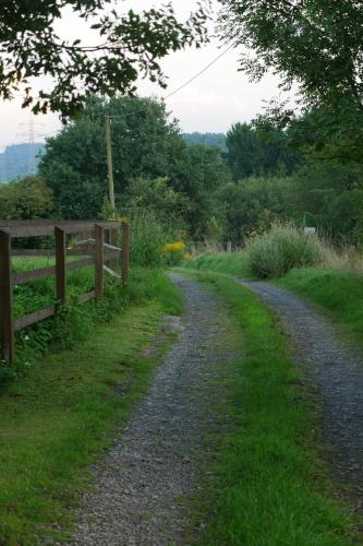 a dirt road with a fence next to a field at Kleine Villa im wilden Garten in Gummersbach
