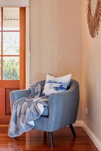 a blue chair with a blanket sitting in a room at Highview House Hunter Valley in Cessnock
