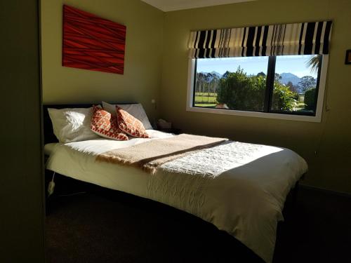1 dormitorio con cama con almohadas y ventana en Kepler Mountain View en Manapouri