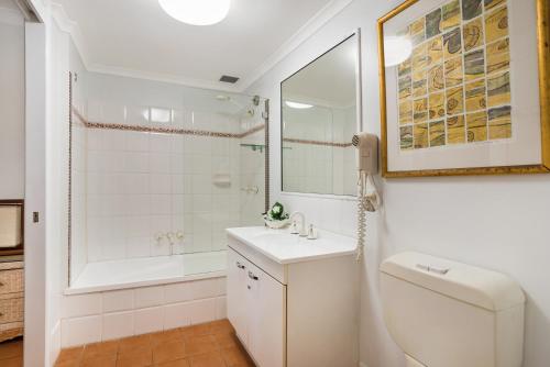 The York Beachfront Holiday Apartments في Yorkeys Knob: حمام مع حوض وحوض استحمام ومرحاض