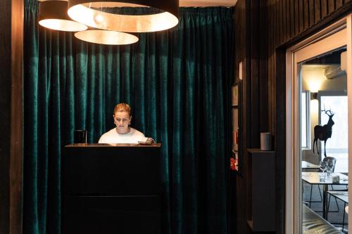 a man sitting at a table in a room with green curtains at Elk at Falls in Falls Creek