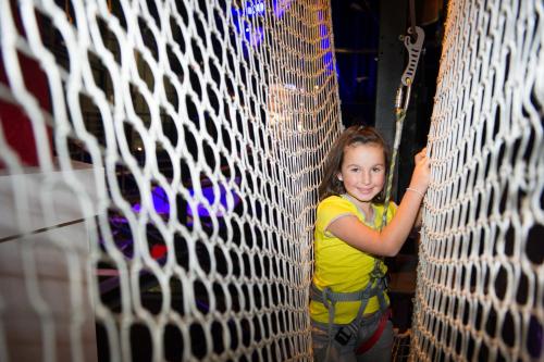 a young girl is standing behind a net at ibis Styles Saint Julien en Genevois Vitam in Neydens