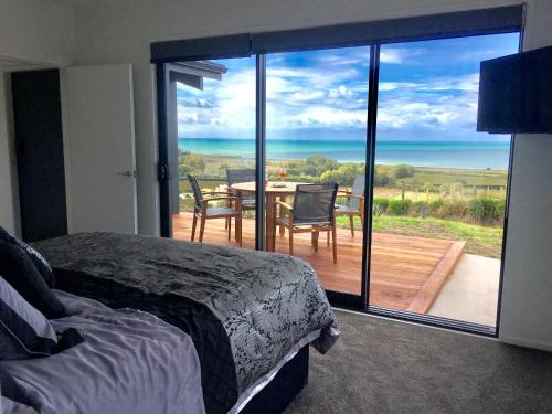 a bedroom with a bed and a balcony with a table and chairs at Chalet Swen Song in Napier
