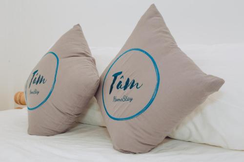 two pillows with the words tim and his shop are on a bed at Tâm Homestay in Hue