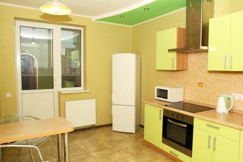 La cuisine est équipée de placards jaunes et d'un réfrigérateur blanc. dans l'établissement Apartments naDobu on Poznyaki - Kiev, à Kiev