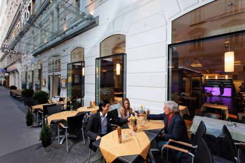 a group of people sitting at tables in a restaurant at Hotel Post Wien in Vienna