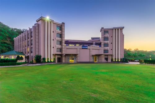 a large building with a green field in front of it at Golden Tulip Chandigarh, Panchkula in Chandīgarh