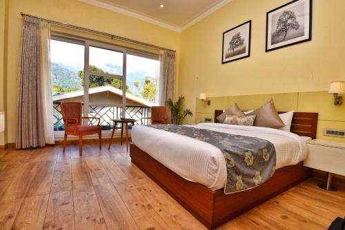 a bedroom with a large bed and a large window at Infinitea Tea Garden Resort in Pālampur