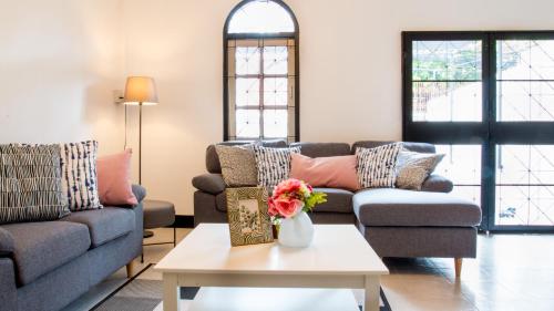 a living room with two couches and a table with flowers at Neveu Premier Residence : Ratchada in Bangkok