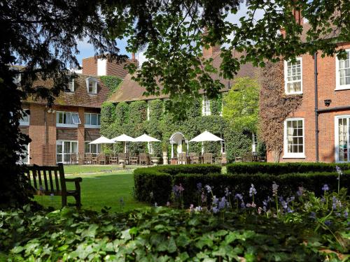 a park with a bench and a building with umbrellas at Bush Hotel Farnham in Farnham