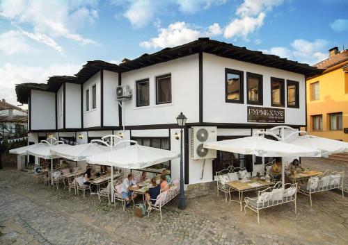 a group of people sitting at tables in front of a building at Гурме хаус in Gabrovo