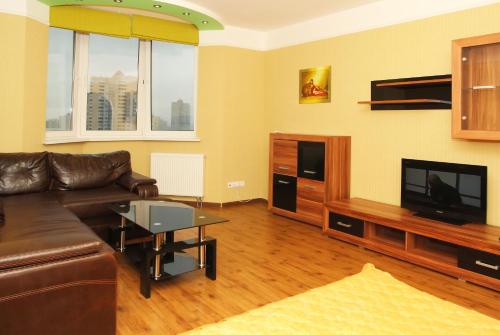 ein Wohnzimmer mit einem Sofa und einem Flachbild-TV in der Unterkunft Apartments naDobu on Poznyaki - Kiev in Kiew