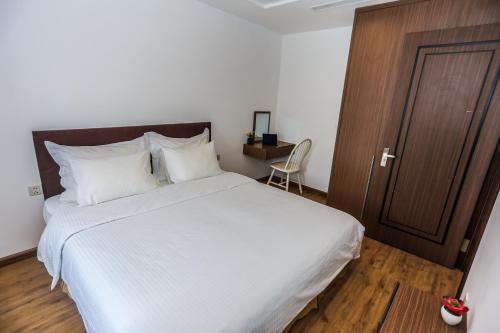 a bedroom with a large white bed and a wooden door at HNC Premier Hotel & Residences in Hanoi