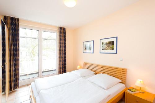 ein Schlafzimmer mit einem Bett und einem großen Fenster in der Unterkunft Villa Hildegard Appartement 8 in Binz