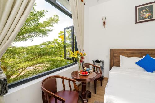sypialnia z łóżkiem, stołem i oknem w obiekcie Blue An Bang Villa w Hoi An
