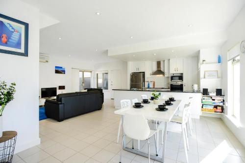 a kitchen and living room with a white table and chairs at Blue Zone - Aldinga Beach - C21 SouthCoast Holidays in Aldinga Beach