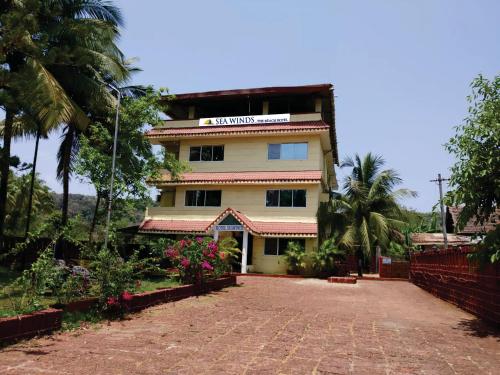 a building with a palm tree in front of it at Sea Winds Hotel, Guhagar in Ratnagiri