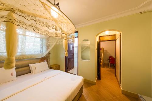 坎帕拉的住宿－Chocolate Luxury Hotel，一间卧室配有一张天蓬床和窗户
