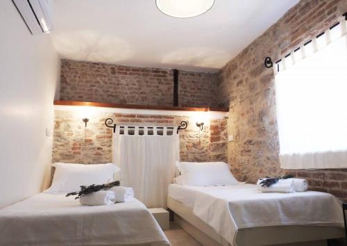 two beds in a room with a brick wall at Küçükköy Otel in Ayvalık