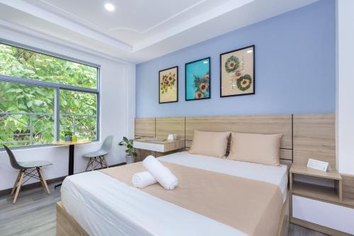 een slaapkamer met een bed, een bureau en een raam bij Cozrum Homes Citi Town in Ho Chi Minh-stad