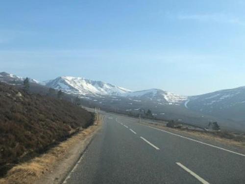 an empty road with snow capped mountains in the background at Taigh d'Luxe in Inverness