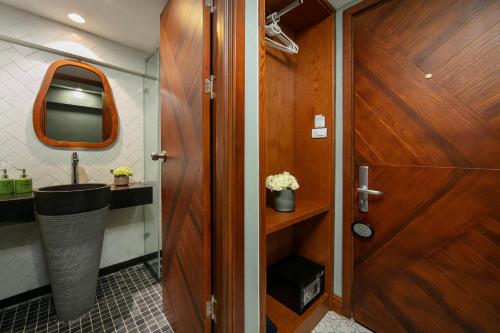 a bathroom with a sink and a wooden door at Hanoi La Selva Central Hotel & Spa in Hanoi
