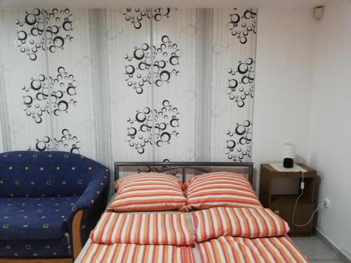 アバッザロークにあるNorbi Apartmanokのベッドルーム1室(ベッド1台、青い椅子付)