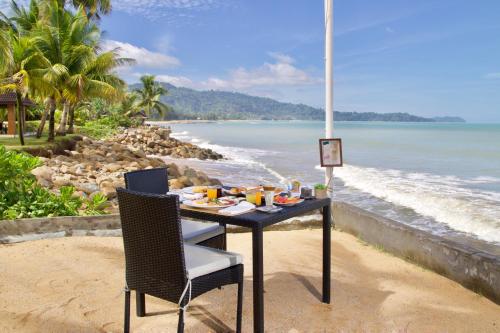 een tafel en stoelen op een strand met de oceaan bij Chongfah Resort Khao Lak - SHA Extra Plus in Khao Lak