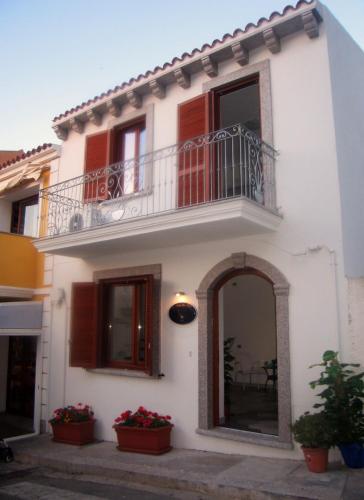 a white house with a balcony and potted plants at Suites de Mar in Santa Teresa Gallura