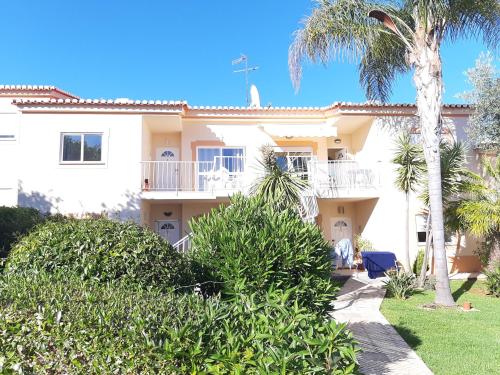 a large white house with palm trees and bushes at Apartment Oasis Park AL in Portimão