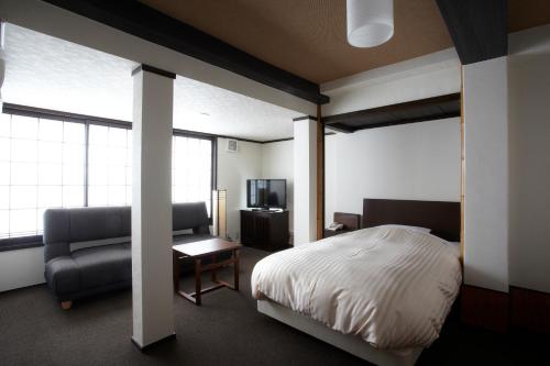 - une chambre avec un lit, un canapé et une chaise dans l'établissement Koyado Enn, à Toyooka
