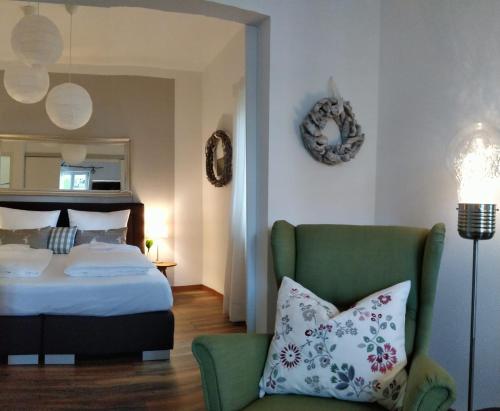 a bedroom with a bed and a green chair at Ferienwohnung WohlfühlEckerl in Tittmoning