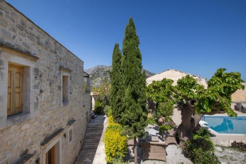a stone house with a tree and a swimming pool at Arcus Suites in Argyroupolis