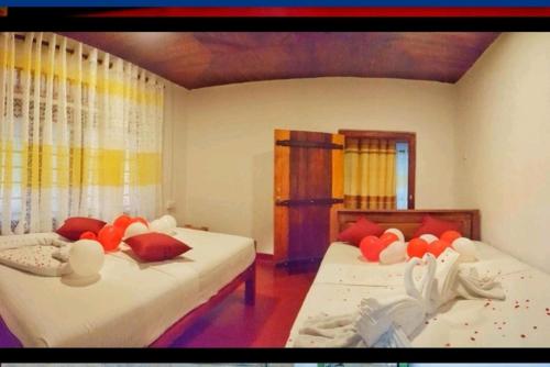 two beds in a room with orange pillows on them at Rainforest Holiday Inn in Deniyaya