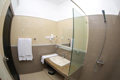 y baño con lavabo y ducha acristalada. en 3R Resort, en Negombo