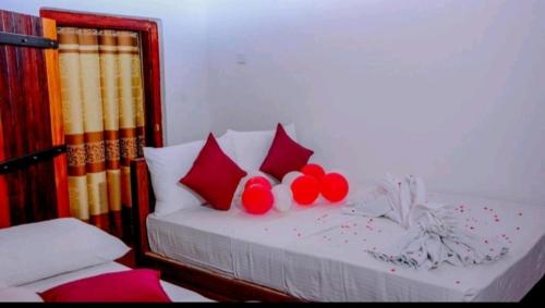 a bed with red pillows and red balls on it at Rainforest Holiday Inn in Deniyaya