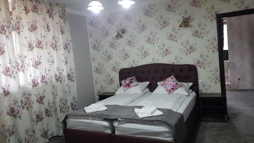 a bedroom with a bed with pink floral wallpaper at Pensiunea Duet in Sărata-Monteoru