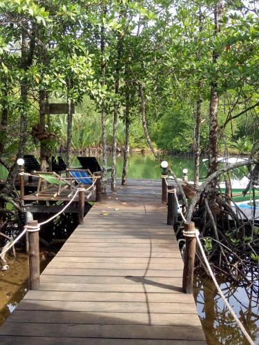 a wooden dock with benches and a boat on the water at TA YAI HOMESTAY (ตา ยาย โฮมสเตย์) in Ko Kood