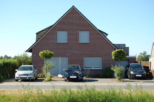 a house with two cars parked in front of it at Ferienwohnung Wiekenblick in Wiesmoor