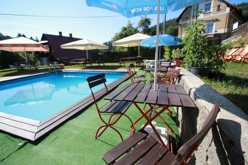 a table with chairs and an umbrella next to a pool at Penzion Paseky U Zapadlych vlastencu in Paseky nad Jizerou