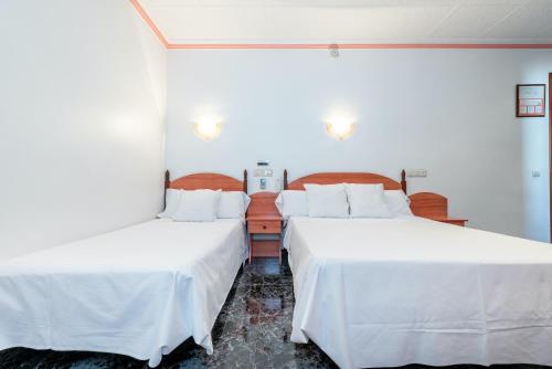 two beds in a room with white sheets at Hotel Canadá in Tarragona