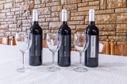 three bottles of wine and two glasses on a table at Hotel Canadá in Tarragona