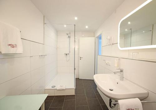 a white bathroom with a sink and a shower at Hotel Brenner in Koblenz