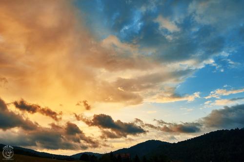 a cloudy sky at sunset with mountains in the background at Osada Chyże Jewki in Cisna